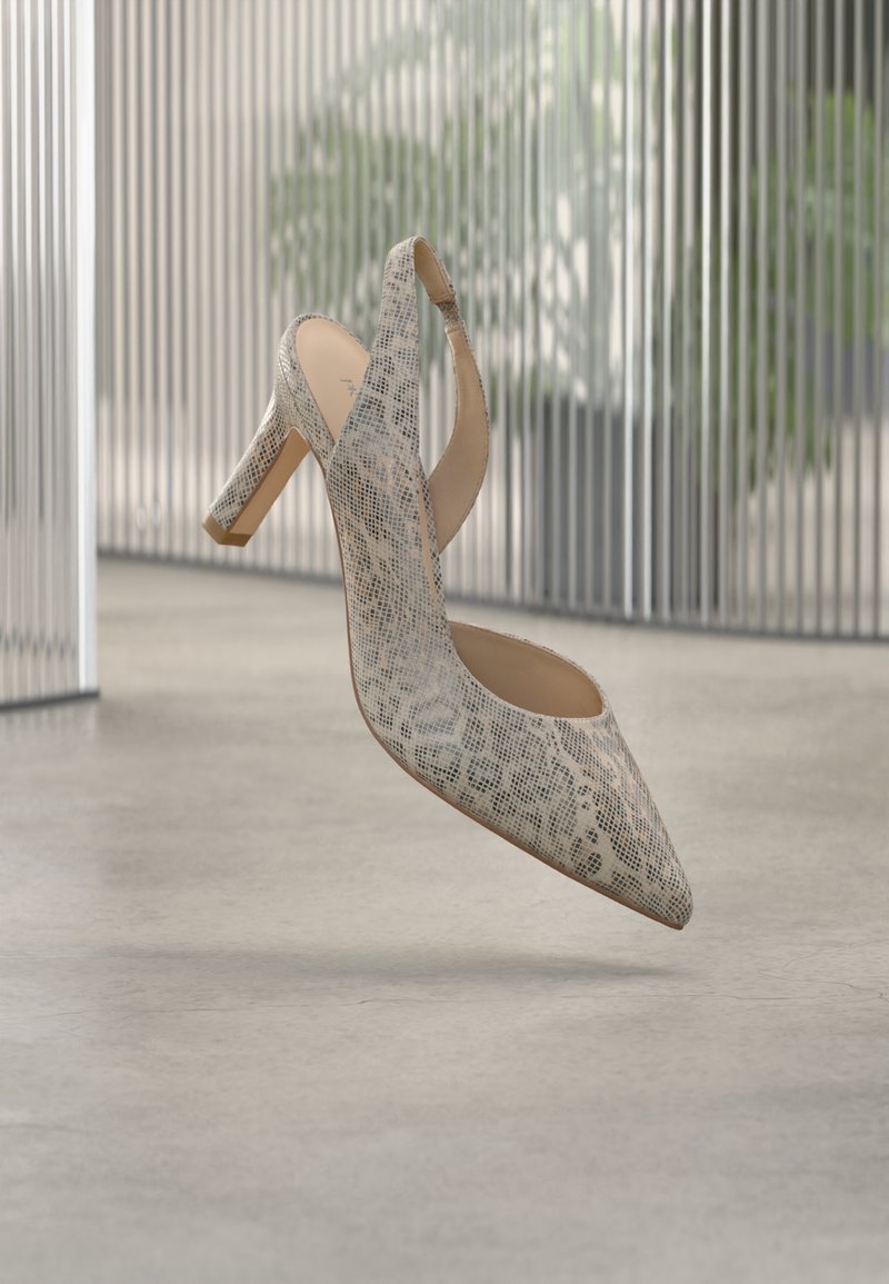 Chaussure à talon haut beige à bride arrière avec motif peau de serpent, bout pointu et talon bloc, exposée à l'intérieur sur un sol en béton lisse.