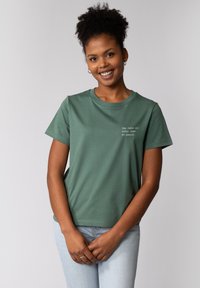 Groene T-shirt met korte mouwen van zachte katoen, met een ronde hals en tekstborduursel op de linkerborst in lichte kleur.
