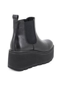 Stivaletto in pelle nera con pannelli elasticizzati ai lati e una suola in gomma spessa. Presenta una punta arrotondata e una linguetta sul retro per facilitarne l'indossamento.