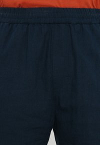 Shorts en tissu léger bleu marine avec une taille élastique, présentant une texture lisse et sans motifs ni accessoires visibles.