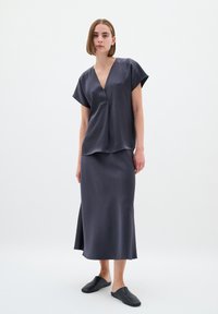 Mørkegrå satin top med V-udskæring og korte ærmer, parret med en matchende midi-nederdel og sorte slip-on sko. Glat tekstur hele vejen igennem.