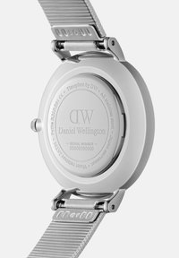 Sudraba Daniel Wellington pulksteņa aizmugure ar metāla sietu siksniņu, iegravēts zīmols, sērijas numurs un ūdens izturības detaļas.