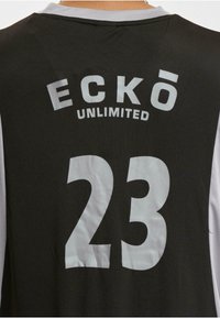 Maillot de sport noir avec des accents blancs, grand texte "ECKŌ UNLIMITED" et le numéro "23" au dos. Tissu doux avec un design à col rond.