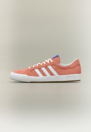 Niskie koralowe buty sportowe z białymi sznurowadłami, trzema białymi paskami z boku, niebieską metką na języku i białą gumową podeszwą.