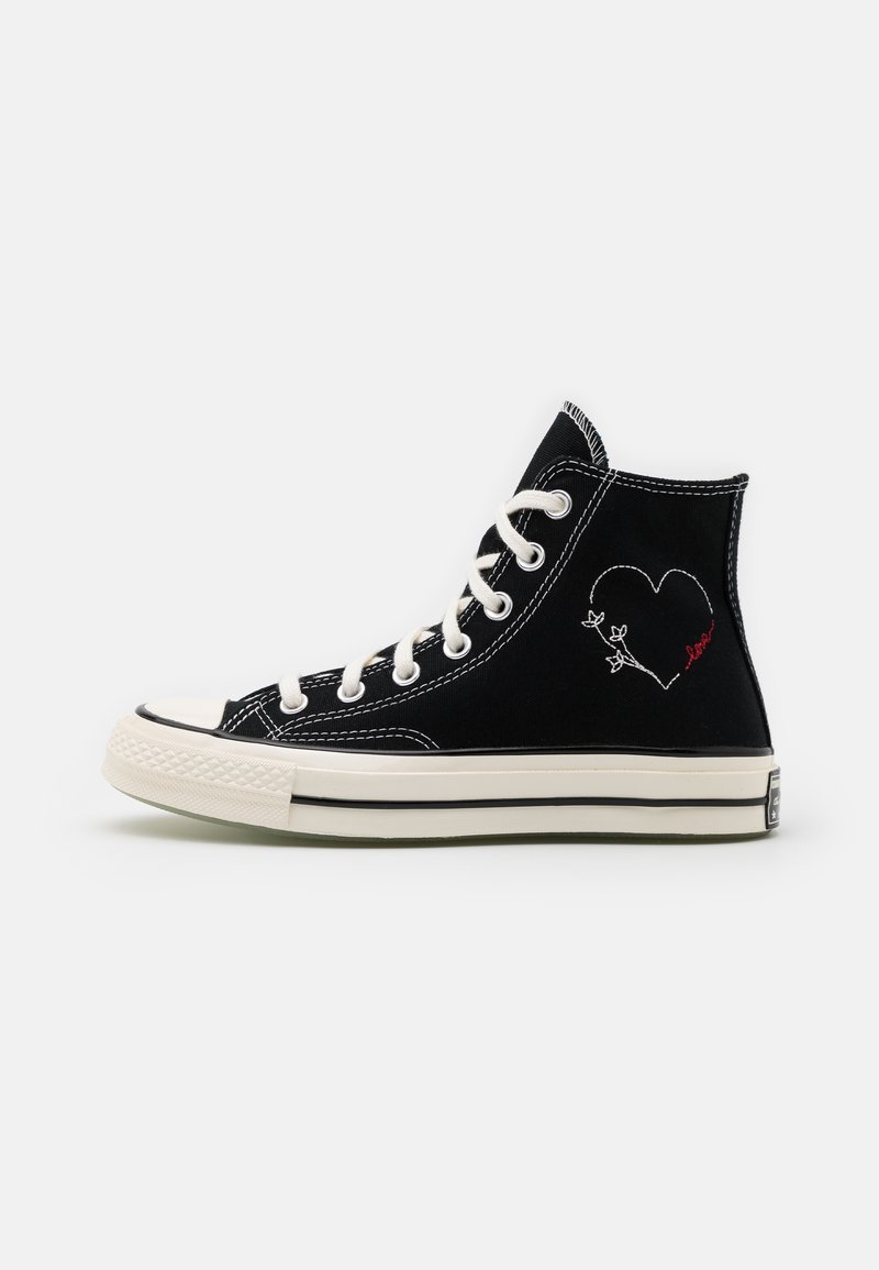 Schwarze High-Top-Sneaker aus Canvas mit weißen Ösen, kontrastierender Naht und einem auf der Außenseite in Weiß und Rot gestickten Herzmotiv.