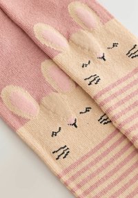Et par lyserøde og beige strikkede sokker med sovende kaninansigt med lukkede øjne, fregner og stribede kraver.