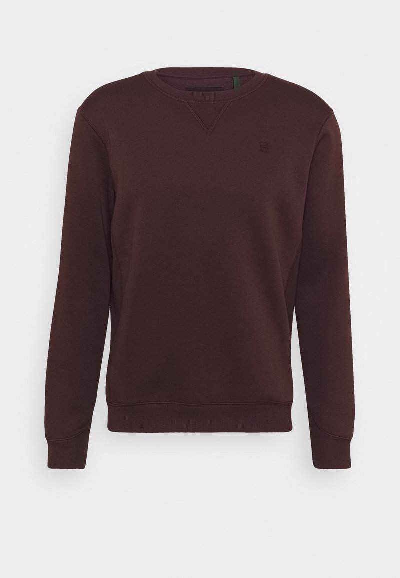 Burgundivärinen huppari, jossa on pyöreä kaula-aukko, ribbireunat ja helma, valmistettu pehmeästä, teksturoidusta kankaasta, jossa on pieni logoyksityiskohta.
