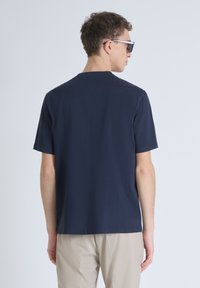 T-shirt blu navy a maniche corte con scollo rotondo, realizzato in tessuto morbido. Mostra un logo discreto sulla parte posteriore del collo.