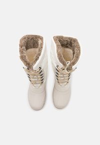 White insulated winter boots with faux fur lining, textured rubber soles, and tan laces. Square toe design with padded upper for warmth.
