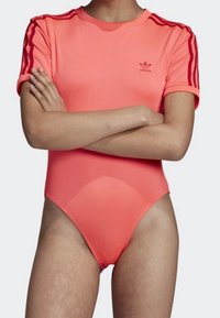 Rosa atletisk bodysuit med korta ärmar, med röda ränder på axlarna och en liten logotyp på bröstet. Slät, elastisk material.