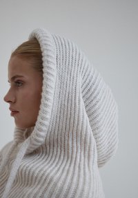 Biała, dziana bluza z kapturem, z dużym, regulowanym, prążkowanym kapturem; charakteryzuje się teksturowanym materiałem z pionowymi paskami. Projekt jest przytulny i otulający.