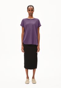 Paarse t-shirt met korte mouwen in een relaxte pasvorm, gecombineerd met een zwarte geribbelde midi rok en lichtbeige instappers.