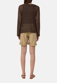 Haut en maille marron à manches longues avec un design texturé, associé à un short beige retroussé et des sandales marron, vu de dos.