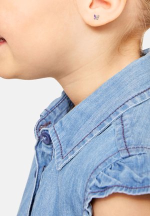 Orecchini a forma di farfalla argentata con accenti viola su un orecchio di un bambino, abbinati a una camicia di jeans azzurro chiaro con colletto e maniche a volant.