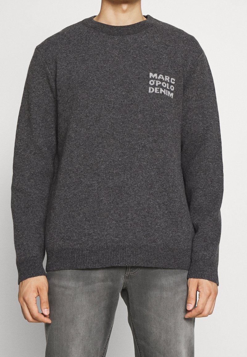 Grafitgrauer gestrickter Pullover mit Rundhalsausschnitt, gerippten Bündchen und Saum. Verfügt über kleinen weißen Logo-Text, der auf der Brust gestickt ist.