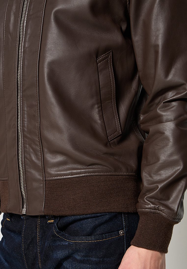 Veste bomber en cuir marron avec fermeture éclair, poignets côtelés et poche latérale, au toucher lisse et au design épuré.
