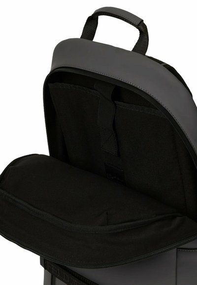 Sac à dos noir avec compartiment principal ouvert montrant une housse rembourrée pour ordinateur portable et une poignée supérieure sur fond blanc.