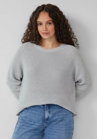 Grauer Strickpullover mit strukturiertem Rippmuster, Rundhalsausschnitt und lockerer Passform. Kombiniert mit blauen Jeans, die einen lässigen Outfit-Stil zeigen.