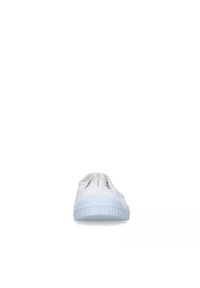 Chaussure blanche à enfiler avec une semelle en caoutchouc texturé, dotée de deux panels élastiques sur les côtés et de coutures noires minimalistes sur l'empeigne.