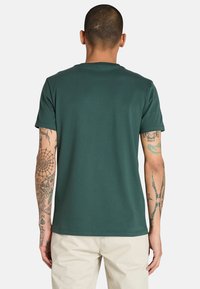 Zelené bavlněné tričko s kulatým výstřihem a krátkými rukávy, s hladkou texturou a minimalistickým designem.