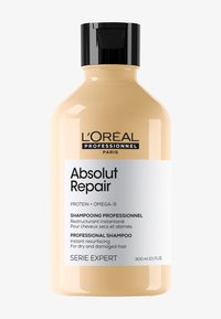 L'Oréal Absolut Repair-sjampo i en rund, ugjennomsiktig beige flaske med svart pumpehette. Har hvit og svart tekst som beskriver produktets fordeler.