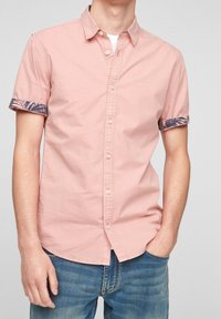 Růžová košile s krátkými rukávy, límečkem a zapínáním na knoflíky, s tmavě modrými vzorovanými manžetami. Vyrobena z lehké bavlněné látky.
