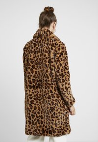 Luipaardprint nepbontjas met een zachte textuur, lange mouwen en een kraag, die tot halverwege het bovenbeen reikt in tinten bruin en zwart.
