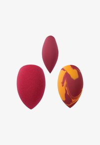 Tre spugnette per il trucco: due di colore rosso solido in varie forme e una marmorizzata arancione e gialla con una consistenza morbida.