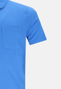 Blå bomulds polo skjorte med brystlomme, korte ærmer og en subtil struktureret finish. Har broderet logo på lommen.