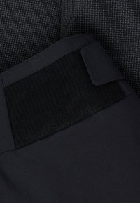 Svart tyg med en slät struktur har en bred, svart elastisk midjeband och en liten, platt hörnflik. Designen är minimal och funktionell.