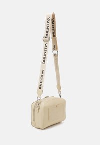 Cream leather bag with a crocodile texture, square shape, zip closure, and a detachable strap with "VALENTINO" printed in black.