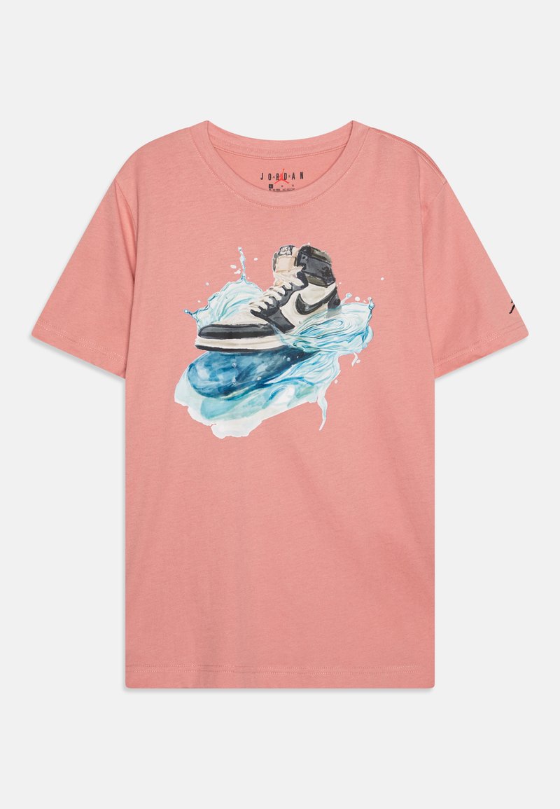 Camiseta de algodón rosa con un gráfico de una zapatilla en blanco y negro salpicando agua. Diseño de manga corta y cuello redondo.