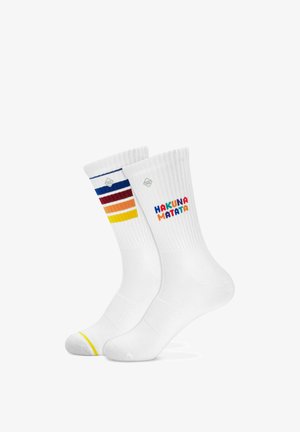Chaussettes blanches montantes avec des bord-côtes, l'une avec des rayures colorées et l'autre avec "HAKUNA MATATA" en lettres multicolores.