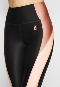 Czarno-różowe legginsy z wysokim stanem, gładką fakturą i kontrastującymi panelami kolorystycznymi; posiadają małe logo na pasie.