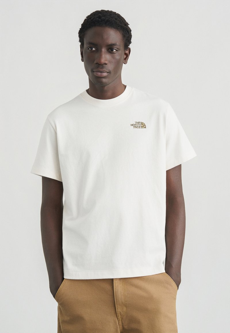 Λευκό βαμβακερό T-shirt με κοντά μανίκια και στρογγυλή λαιμόκοψη. Διαθέτει ένα μικρό, κεντημένο λογότυπο στο αριστερό στήθος σε σκούρους τόνους.