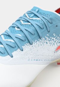 Baskets de sport bleu et blanc avec surface texturée, dotées de lacets bleus et de la marque "CARBON INFUSED", accents de semelle jaune.