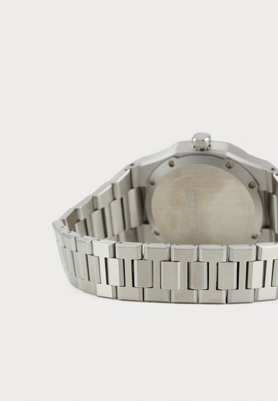 Silberner Edelstahl-Uhren mit einem breiten Gliederarmband, quadratischem Gehäuse, glatter Oberfläche und einem schlichten runden Rückenteil mit zentraler Krone.