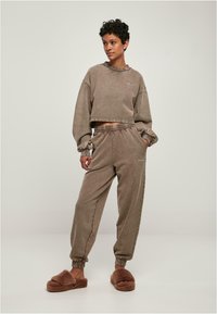 Brun cropped hettegenser med puffede ermer og matchende bukser med elastisk liv; fleece tøfler fullfører det avslappede antrekket.