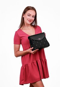 Černá syntetická kabelka s klopou a barevnými tečkami. Disponuje jednoduchým designem s horním uchopem a logem.