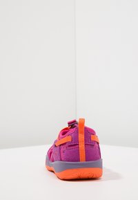Lilla og oransje barnsko med suede-materiale, bakre trekkinn, og en teksturert gummisåle. Har justerbare remmer for passform.
