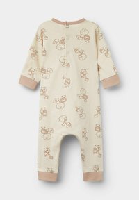Krémový dětský overal s dlouhými rukávy, zdobený světle hnědými vzory zvířat a kontrastními manžetami. Zapínání na zádech pomocí druků.