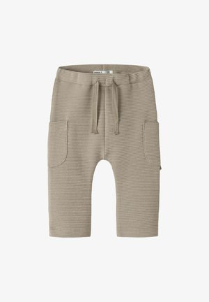 Pantalon bébé en maille côtelée beige avec une taille élastique, un cordon de serrage et deux grandes poches avant.