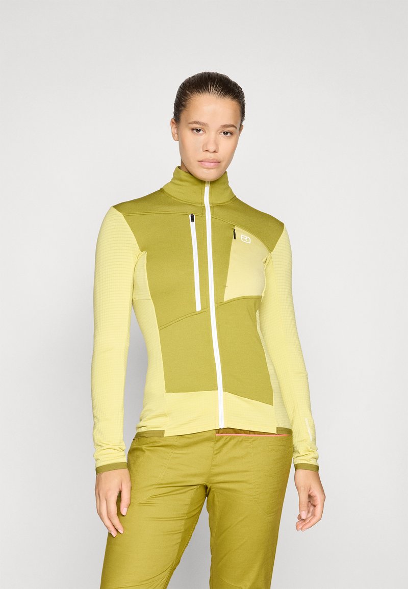 Langärmlige, Reißverschlussjacke in Grüntönen mit hohem Kragen, strukturiertem Stoff und geometrischem Paneldesign. Verfügt über zwei Reißverschluss-Taschen auf der Vorderseite.