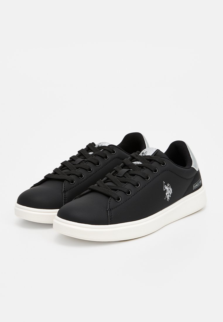 Zapatillas de deporte de piel sintética negra con suelas de goma blanca, cordones negros, acentos plateados y un logo en el costado. Diseño de punta redonda.