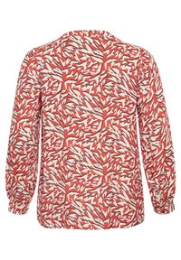 Blusa de manga larga con fondo rojo que presenta un patrón de hojas en blanco y negro, tejido suave, escote redondo y puños fruncidos.