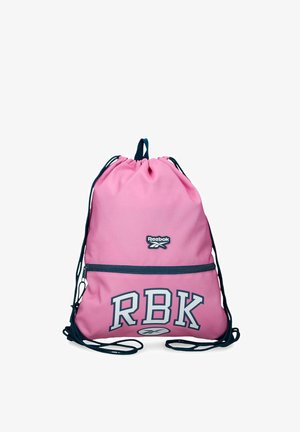 Mochila rosa con cordones negros, bolsillo delantero con cremallera, letras "RBK" y logotipo de Reebok sobre fondo blanco.