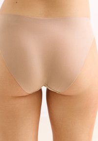 Beige hooggecutte slip met een gladde textuur en naadloze randen. Het ontwerp biedt volledige dekking en een schone, minimalistische uitstraling.