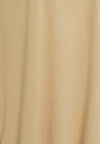 Tissu beige uni avec de subtiles plis verticaux et une texture lisse et mate.