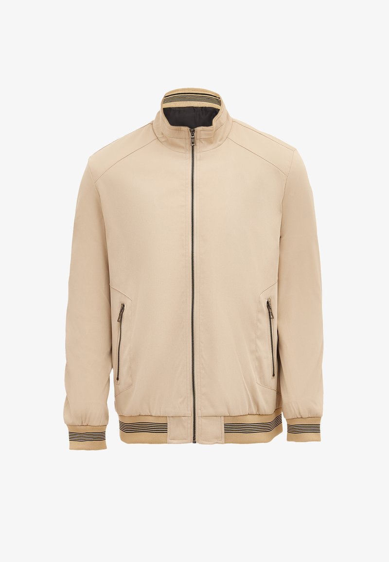 Beige bunda s vyvýšeným límcem, zipem v přední části, dvěma zipovými bočními kapsami a pruhovanými žebrovanými manžetami a dolním lemem. Hladká textilie.