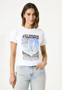 Camiseta de algodón blanca con un estampado gráfico que incluye texto colorido y un diseño de flores. Tiene un ajuste relajado con mangas cortas. Jeans de mezclilla azul claro.